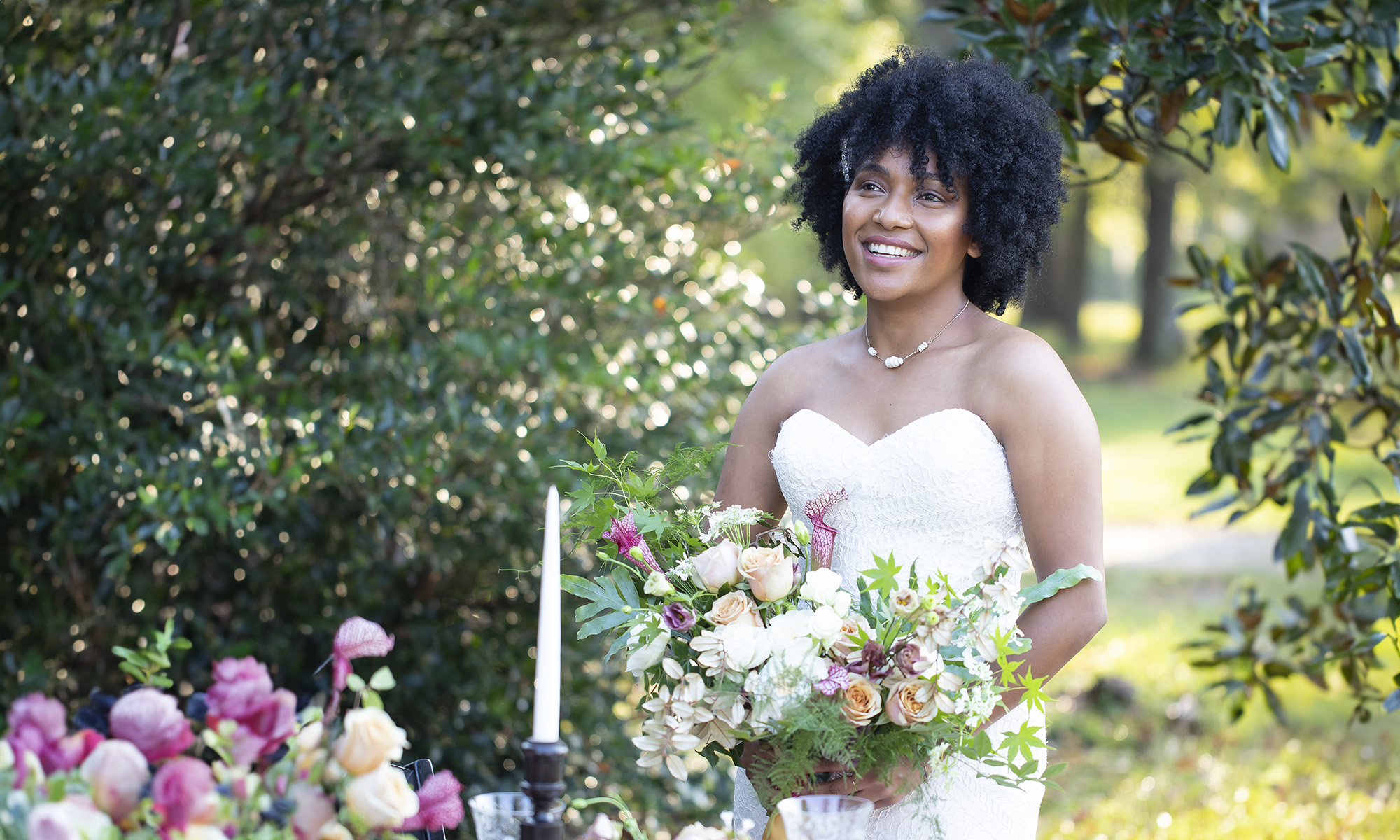 Blush Bridal and Formal Wear - bride in natural hair outdoors in strapless wedding dress holding a bouquet